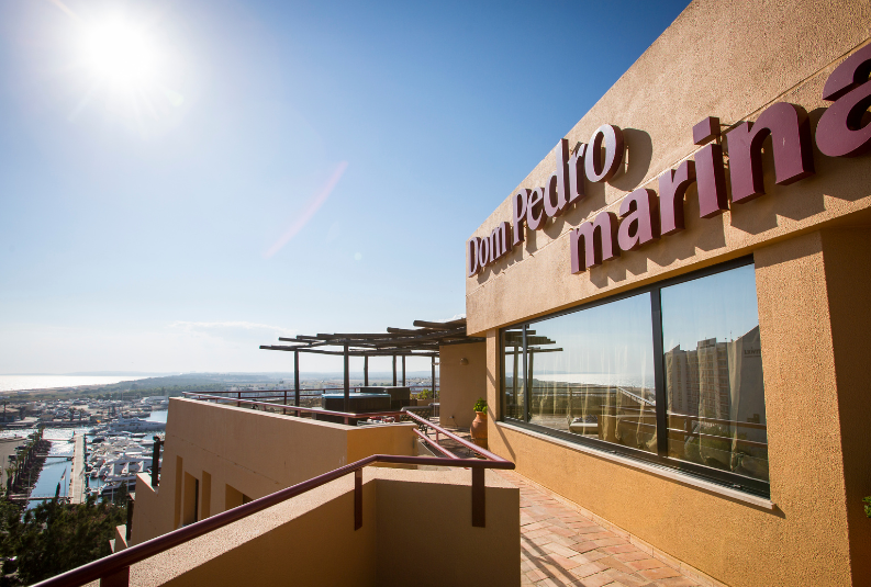 Dom Pedro Marina hotel façade with Vilamoura Marina in the background at sunset. 4o