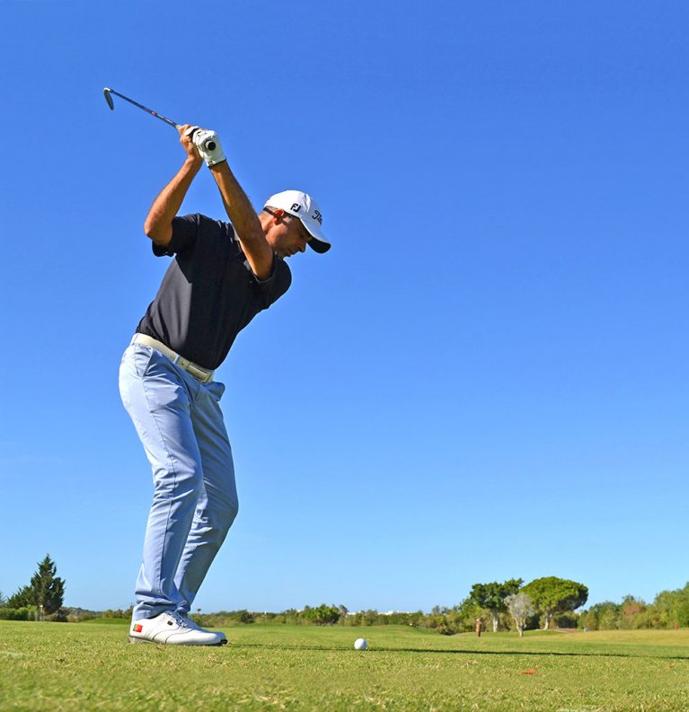 Golfista a dar uma tacada no fairway.